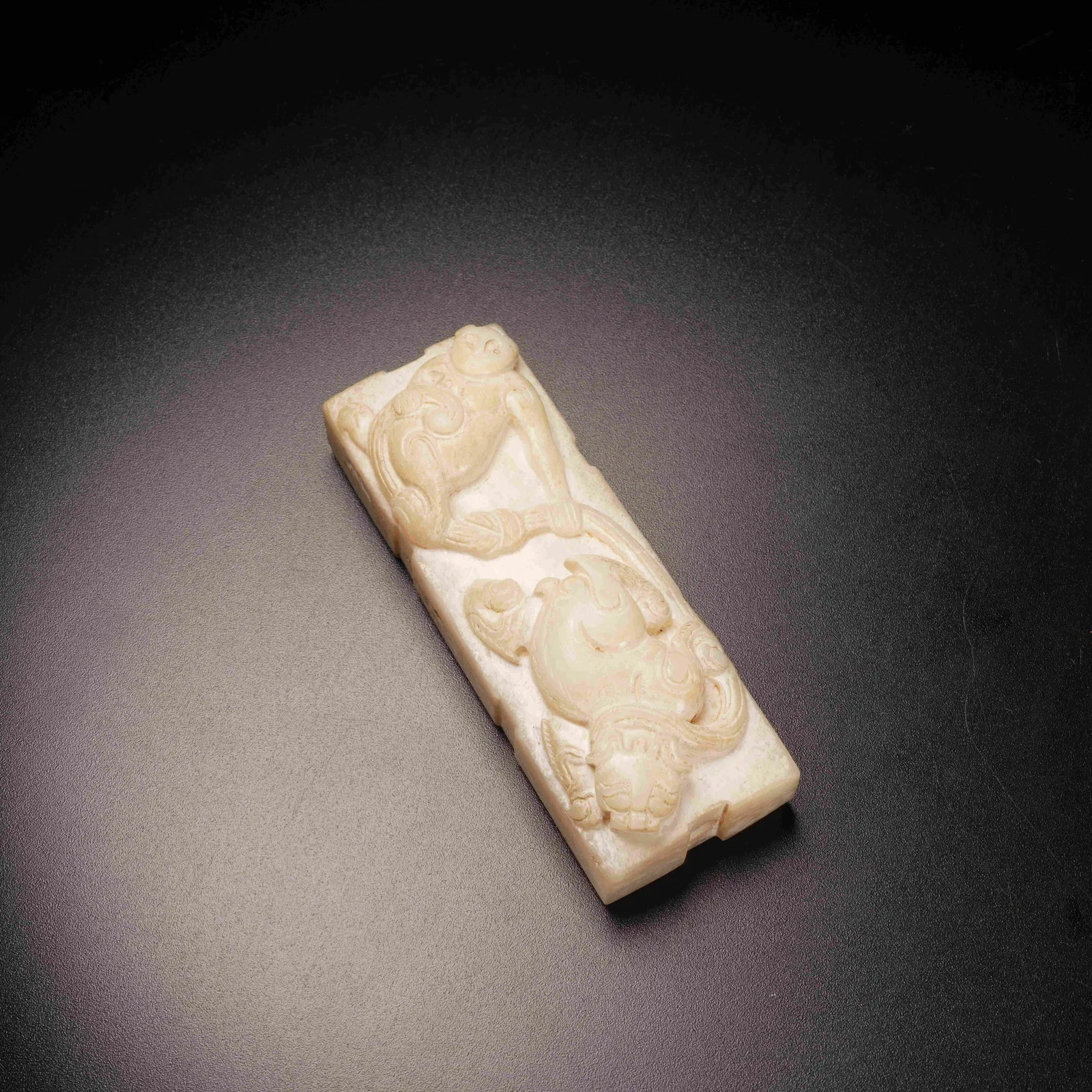 A ANCIENT JADE TOGGLE WITH DIVINE HUMAN PLAYING WITH BEAST MOTIF