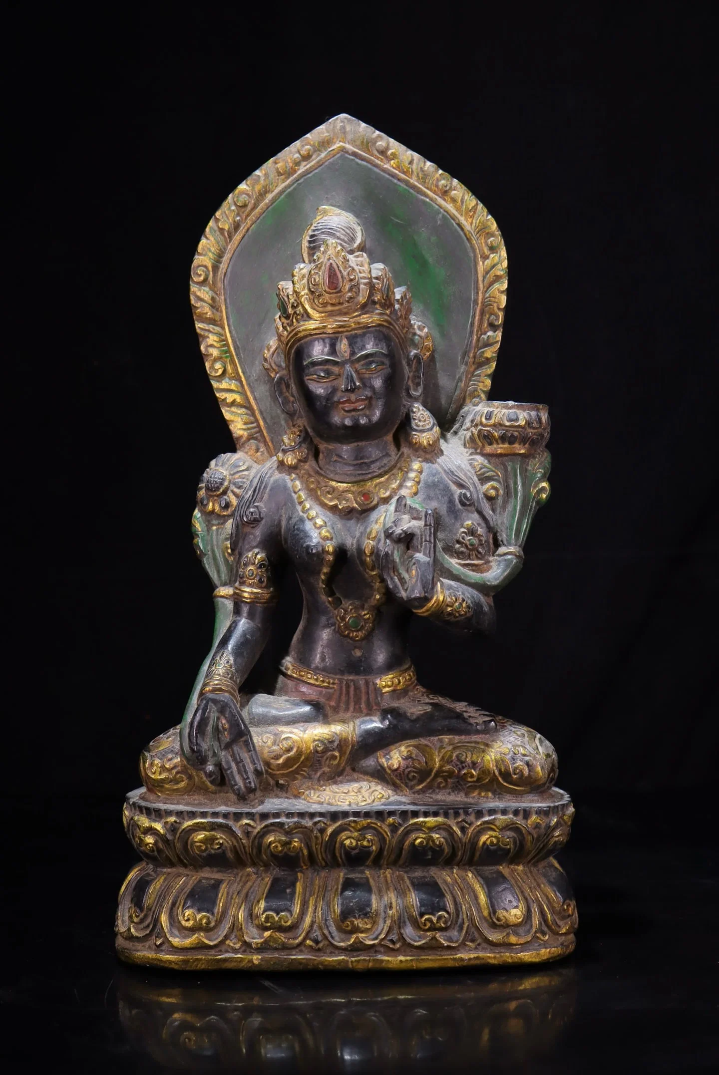 A beautiful statue of Green Tara in black stone with gold painting