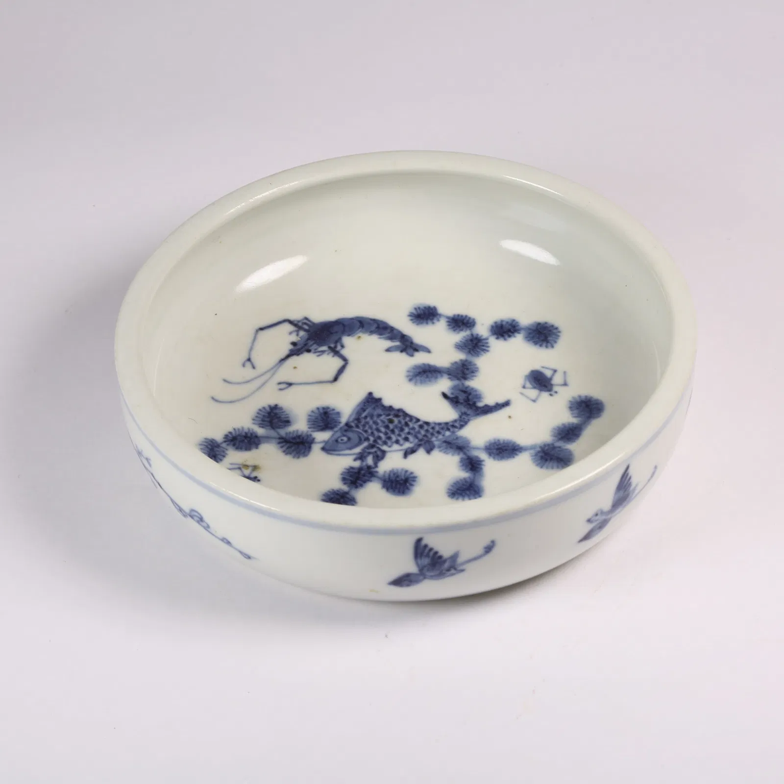 A BLUE AND WHITE SMALL DISH WITH FISH AND ALGAE MOTIF