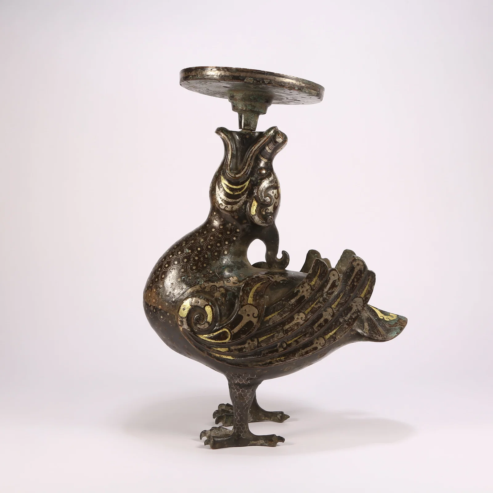 A BRONZE CANDLEHOLDER IN THE FORM OF A DIVINE PHOENIX WITH GILT-INLAID GOLD AND SILVER