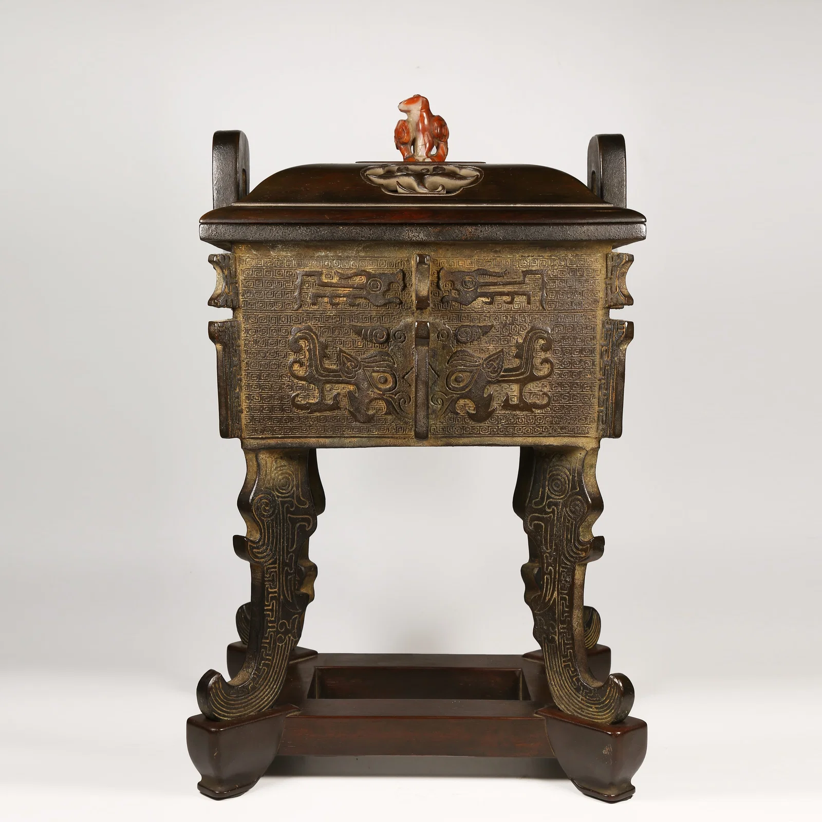 A BRONZE DING-SHAPED CENSER WITH FOUR LEGS AND ANIMAL-FACE MOTIFS, UPRIGHT FINIALS