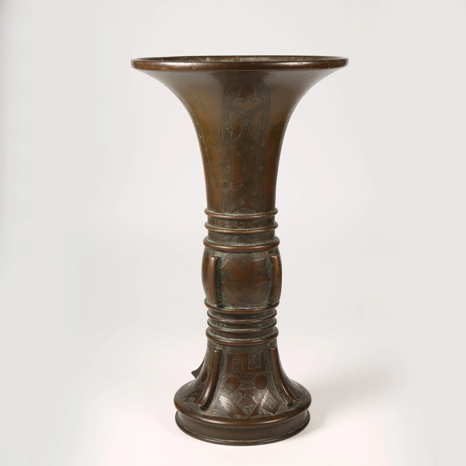 A BRONZE GU VESSEL WITH UPRIGHT FINIALS AND STRING PATTERN DECORATION