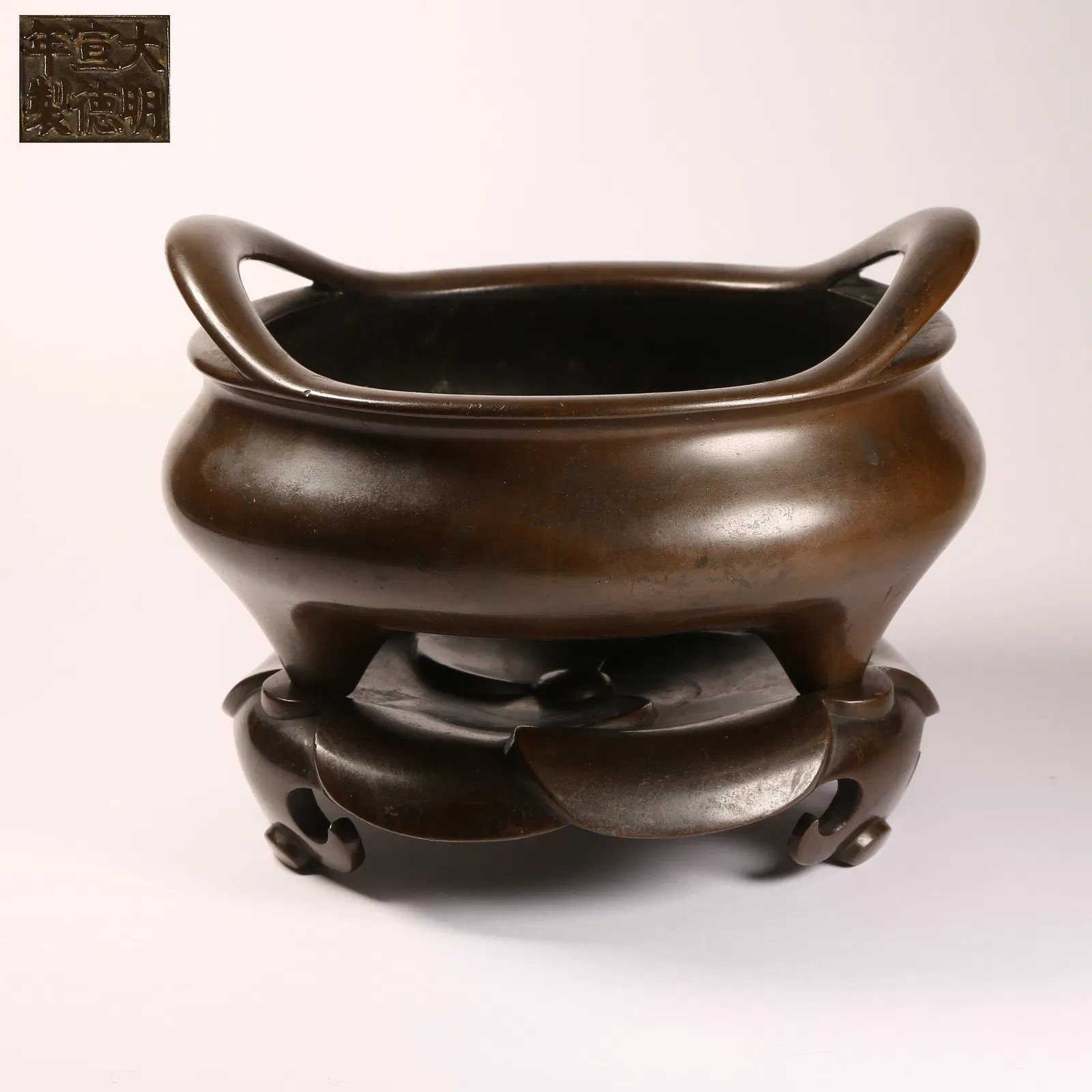 A BRONZE THREE-LEGGED BRIDGE-HANDLED CENSER WITH CONNECTED BASE