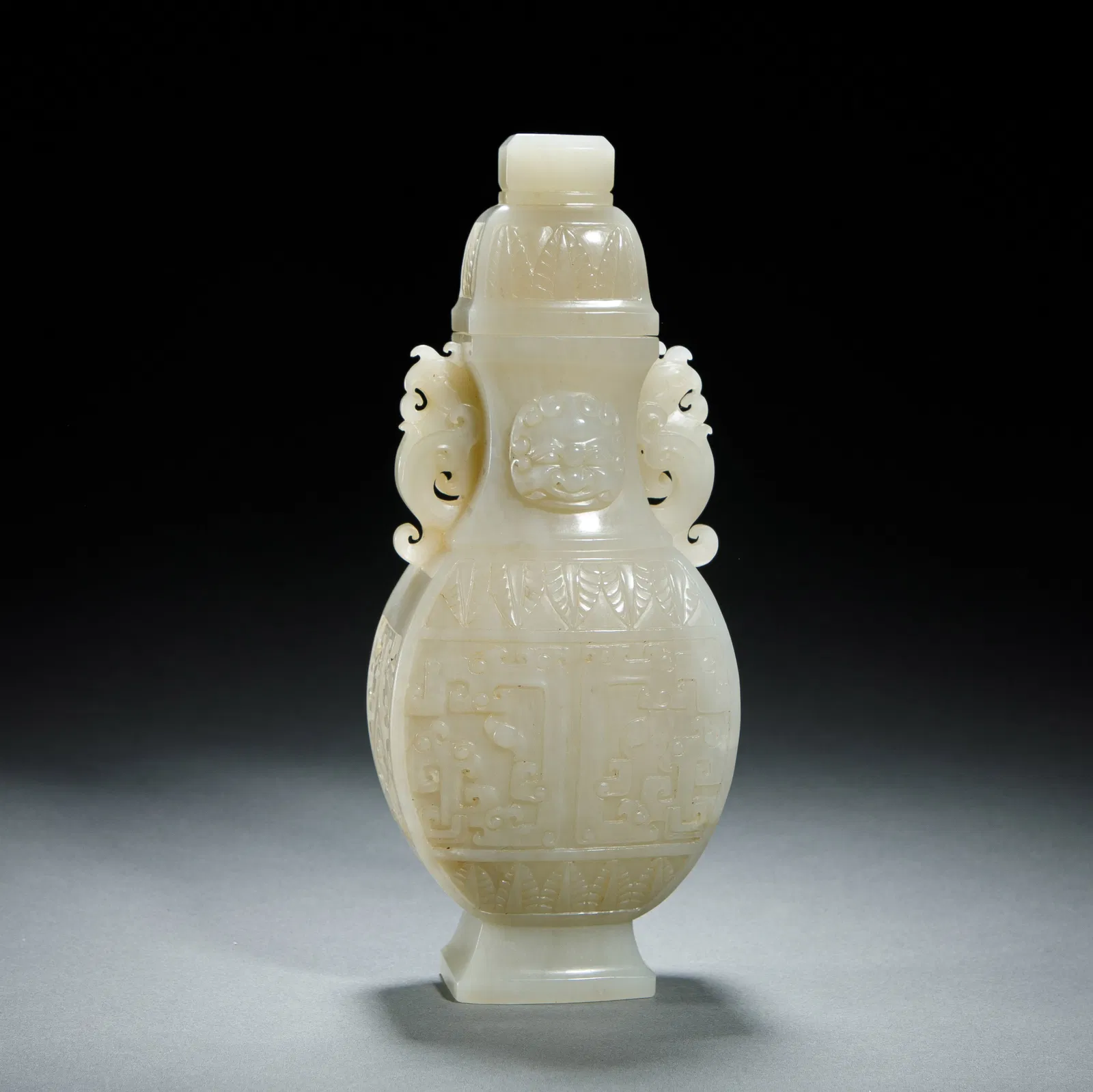 A CHINESE ARCHAISTIC CARVED WHITE JADE VASE WITH COVER