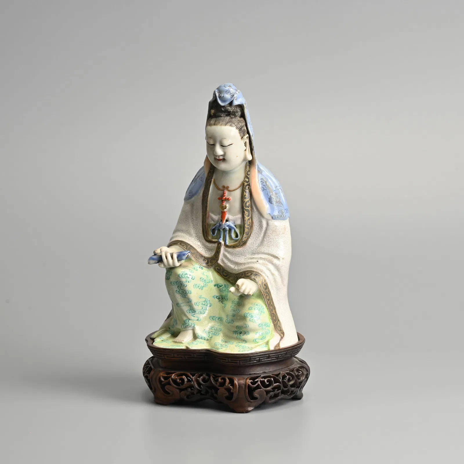 A CHINESE FAMILLE ROSE PORCELAIN FIGURE OF GUANYIN ON HARDWOOD STAND, QING DYNASTY.