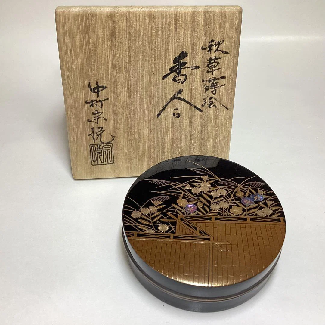 A circular incense box designed by Nakamura SOetsu, decorated with maki-e (gold lacquer) and