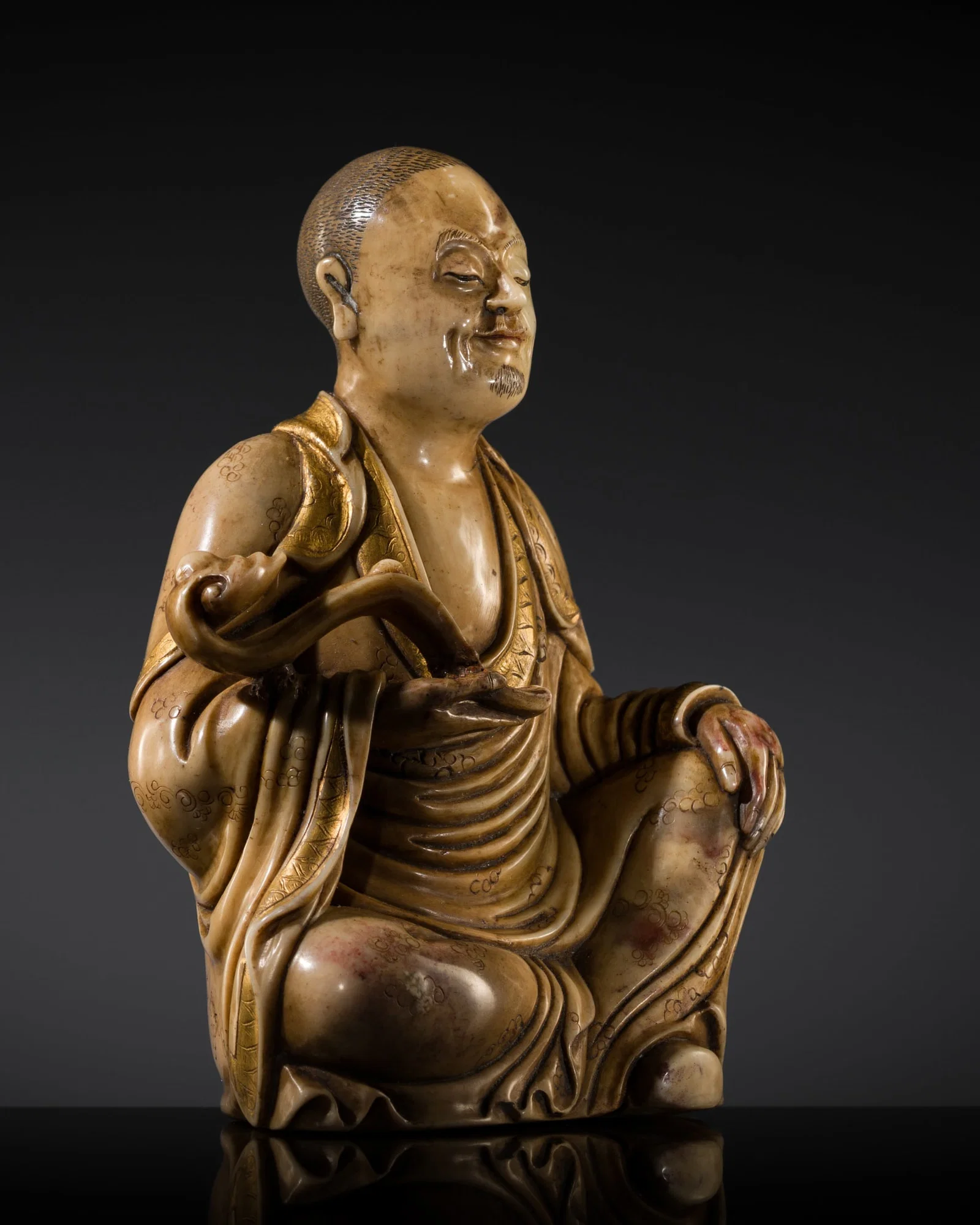 A FINE PARCEL-GILT SHOUSHAN SOAPSTONE FIGURE OF A LUOHAN, 17TH-18TH CENTURY