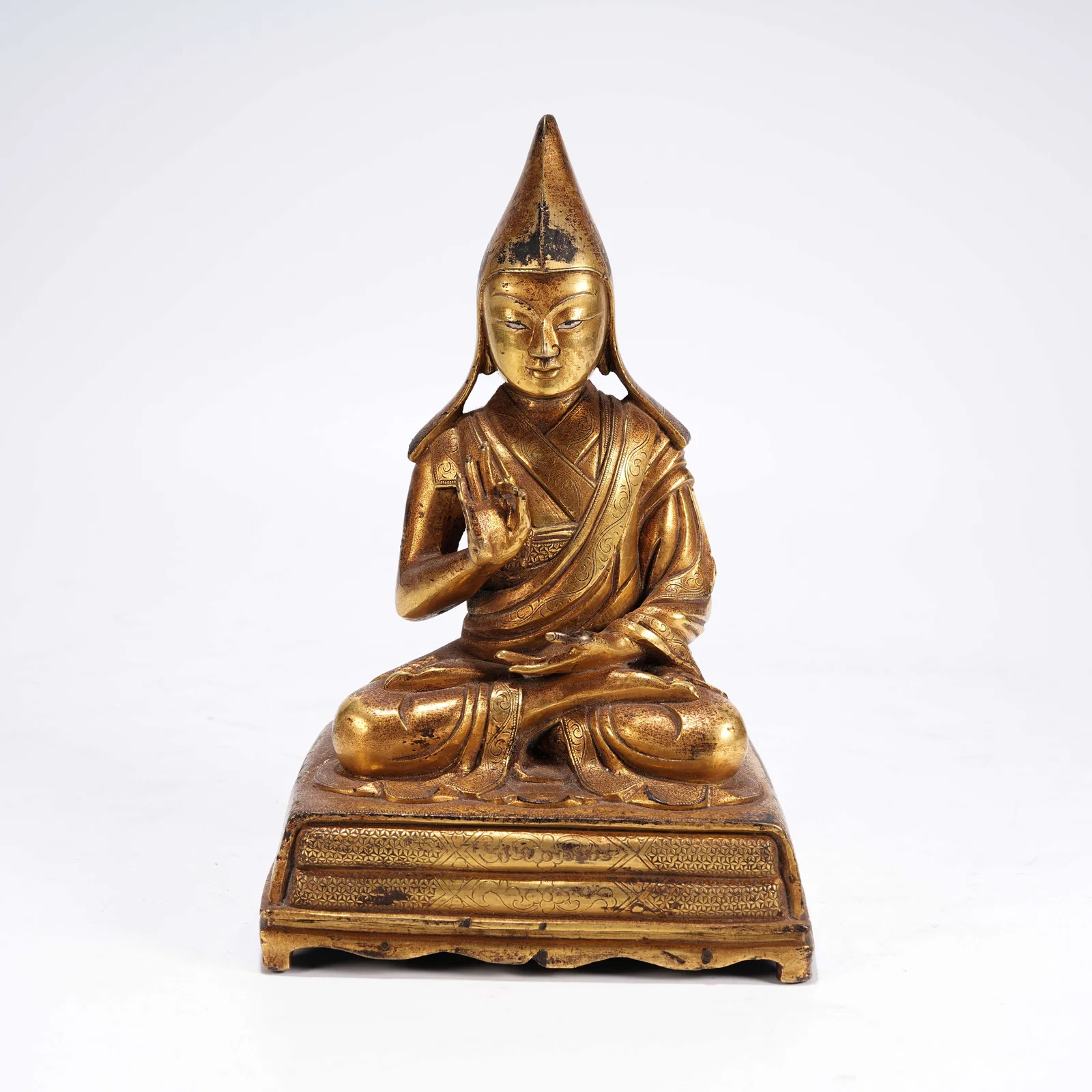 A GILT-BRONZE SEATED LAMA FIGURE
