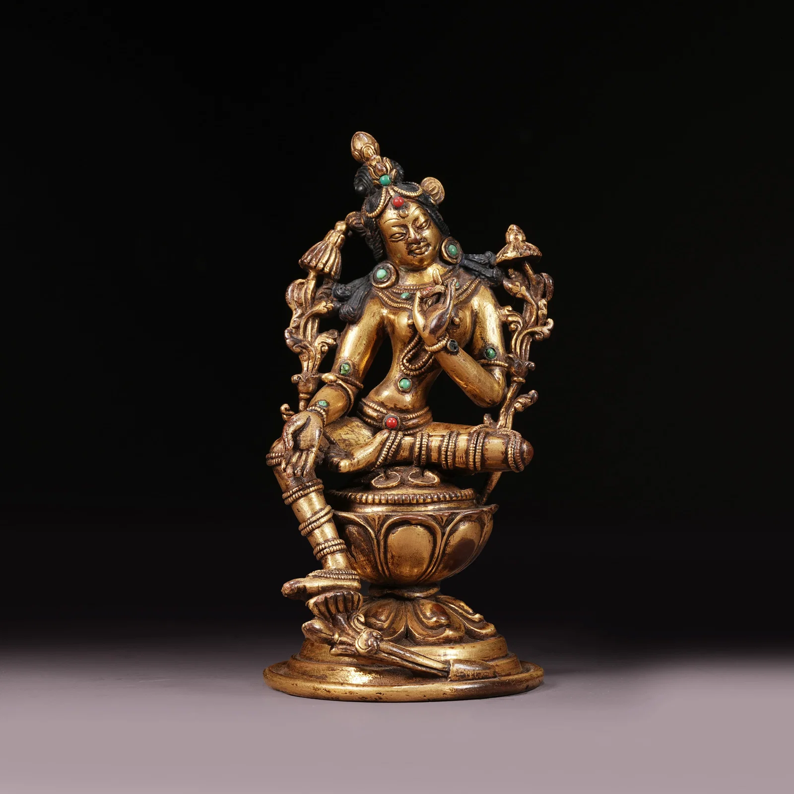 A GILT BRONZE STATUE OF GREEN TARA INLAID WITH GEMS