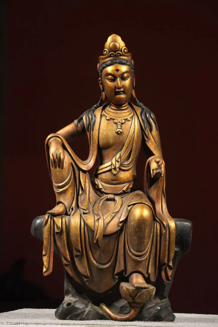 A GILT-LACQUERED WOOD FIGURE OF GUANYIN IN ROYAL EASE, MING DYNASTY, 14TH–17TH CENTURY
