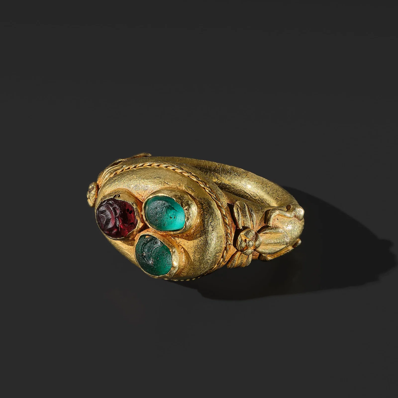 A GOLD AND GLASS PASTE 'THREE BUDDHIST JEWELS' (TRIRATNA) RING, JAVA, CIRCA 12TH CENTURY