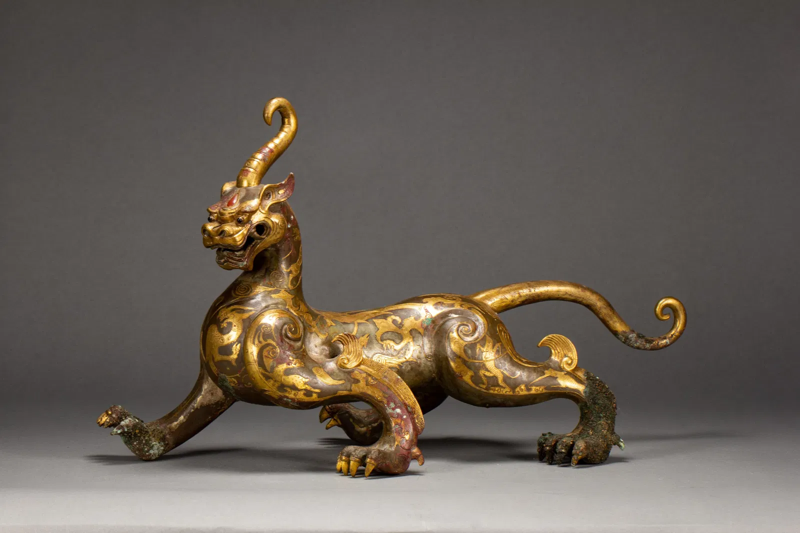 A GOLD AND SILVER INLAID BRONZE MYTHICAL BEAST