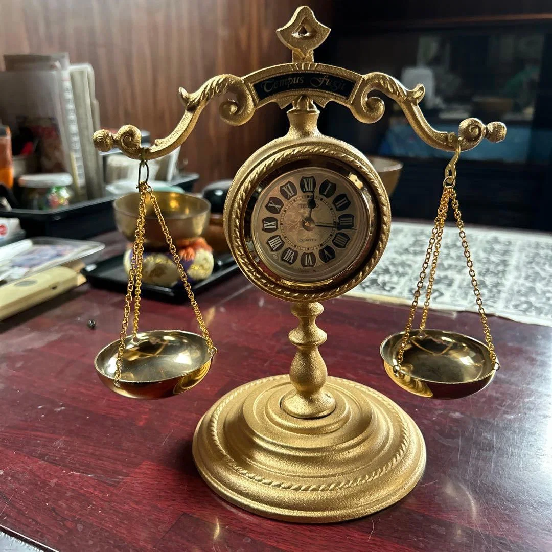 A gold balance with a clock, approximately 30 centimeters.