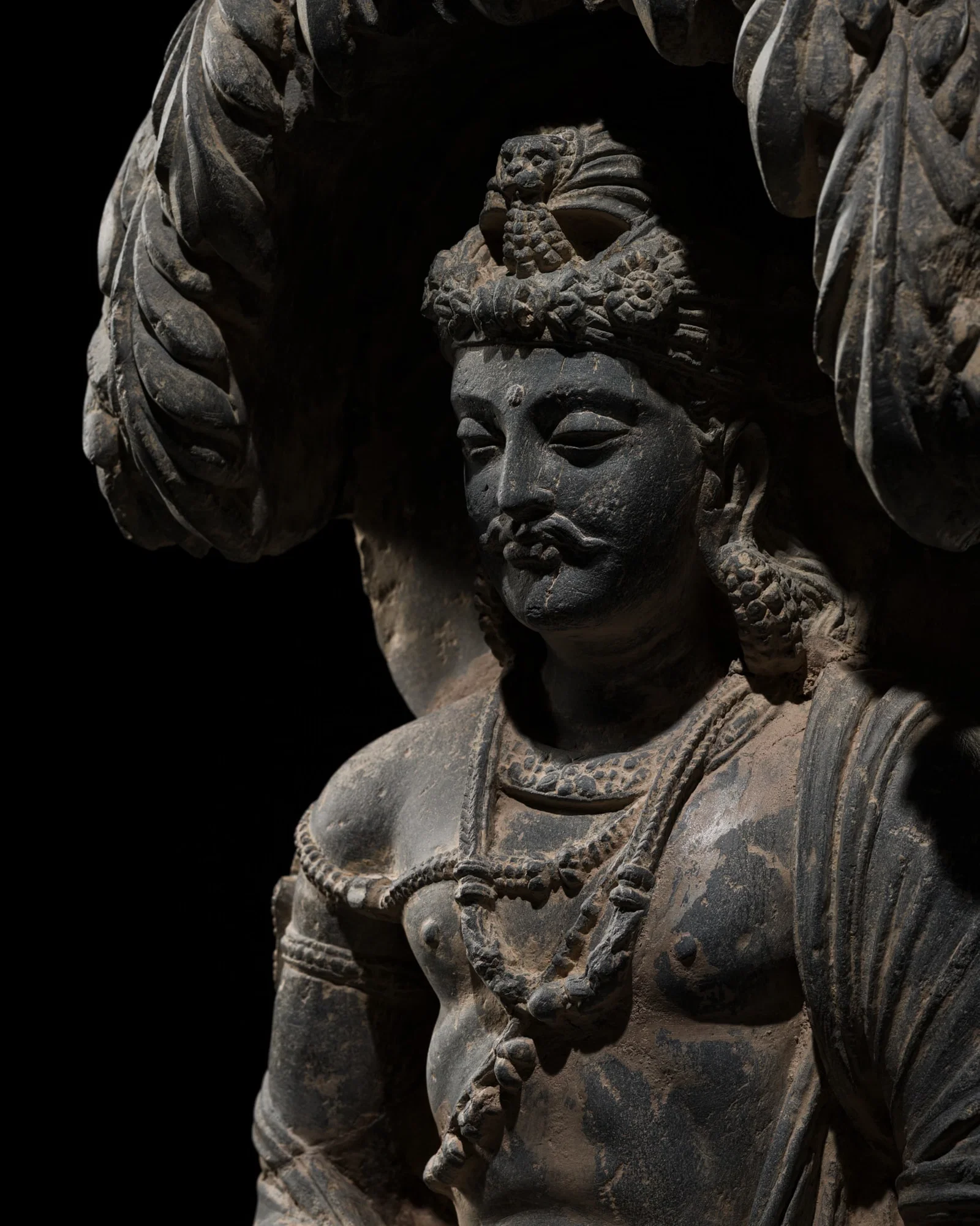 A GRAY SCHIST FIGURE OF GAUTAMA SIDDHARTHA MEDITATING UNDER THE JAMBU TREE, ANCIENT REGION OF