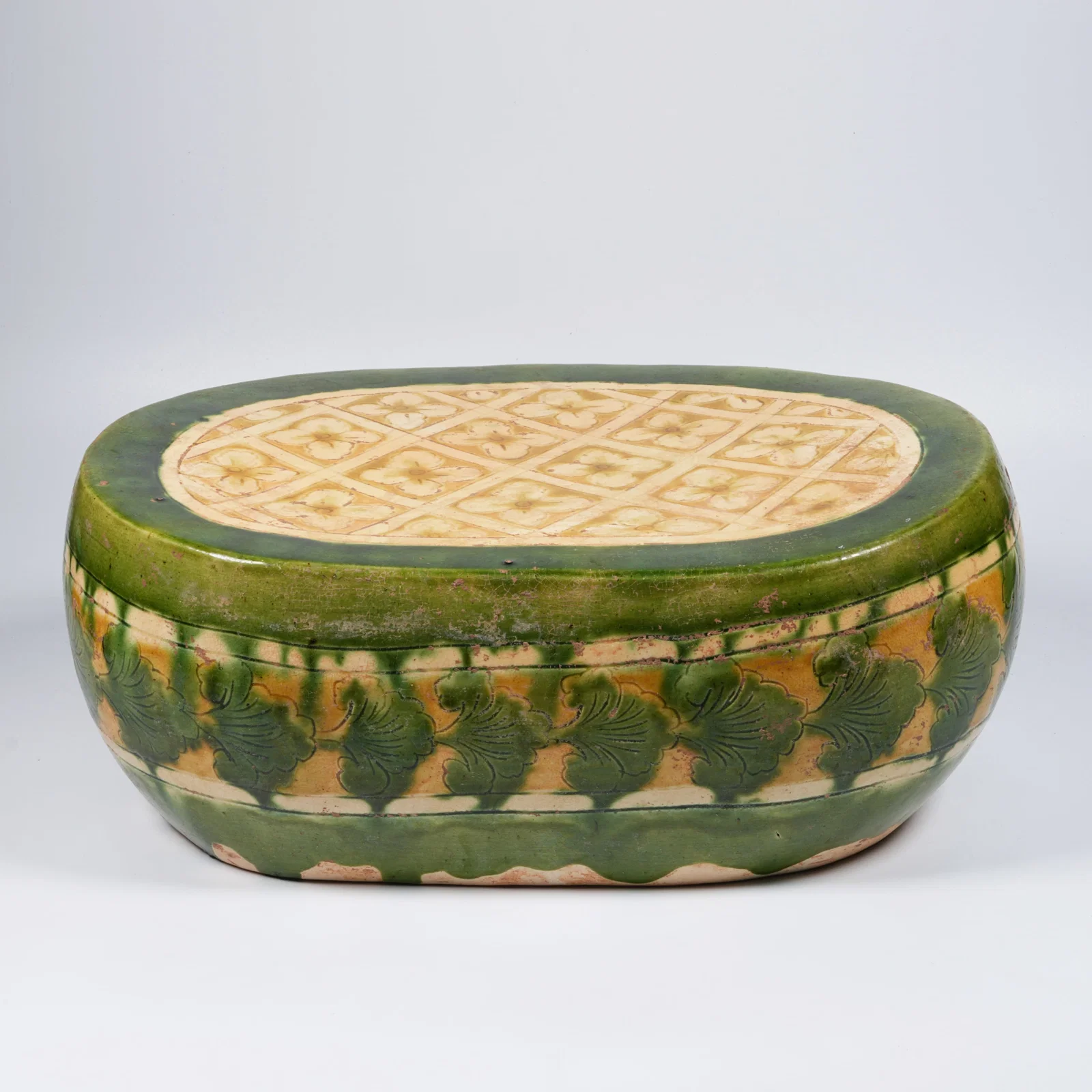 A GREEN-GLAZED PORCELAIN PILLOW WITH FLORAL MOTIF