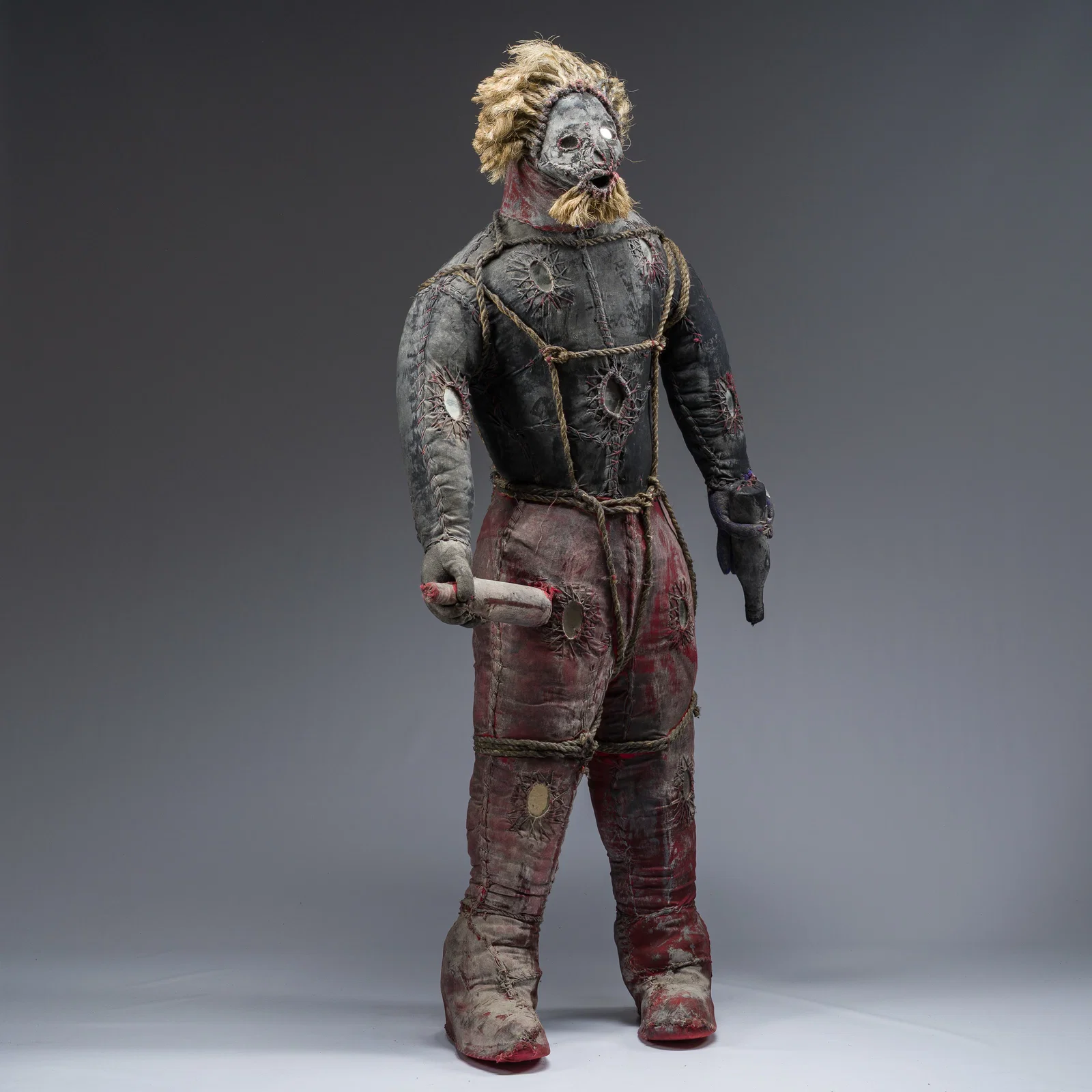 A Haitian Bizango sculpture of a hairy figure with a bottle in both hands, mixed media, 20th C.