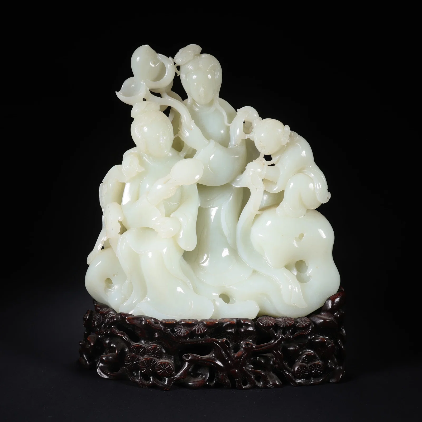 A HETIAN JADE DOUBLE GIRL PLAYING WITH CHILD ORNAMENT ON WOODEN BASE