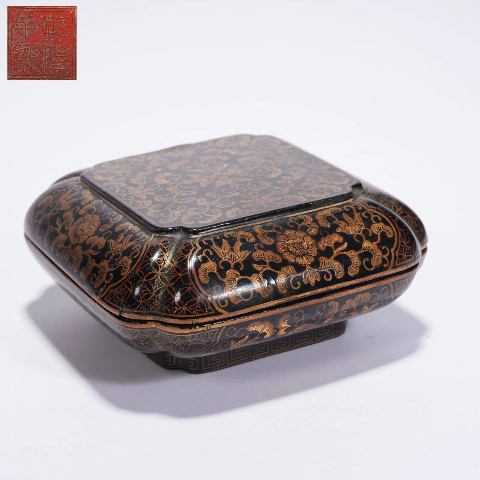 A LACQUERED COVERED BOX WITH GILT FLORAL DECORATION