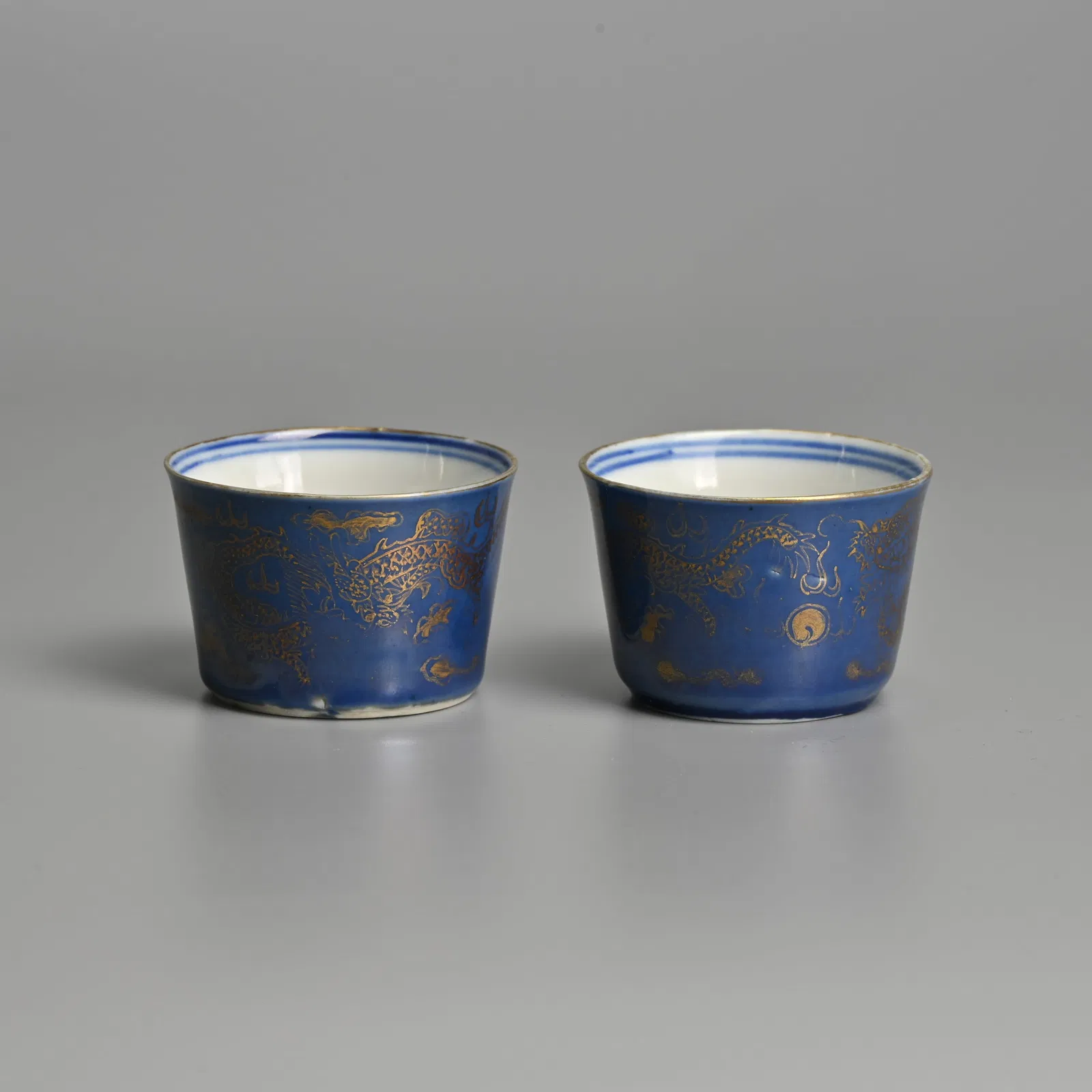 A PAIR OF CHINESE BLUE-GROUND AND GILT DECORATED 'DRAGON' PORCELAIN CUPS, QING DYNASTY.