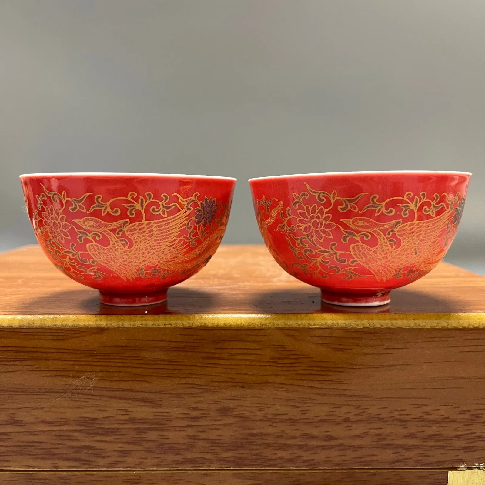 A pair of red-ground gilt-painted porcelain cups with double phoenixes and lotus patterns from the