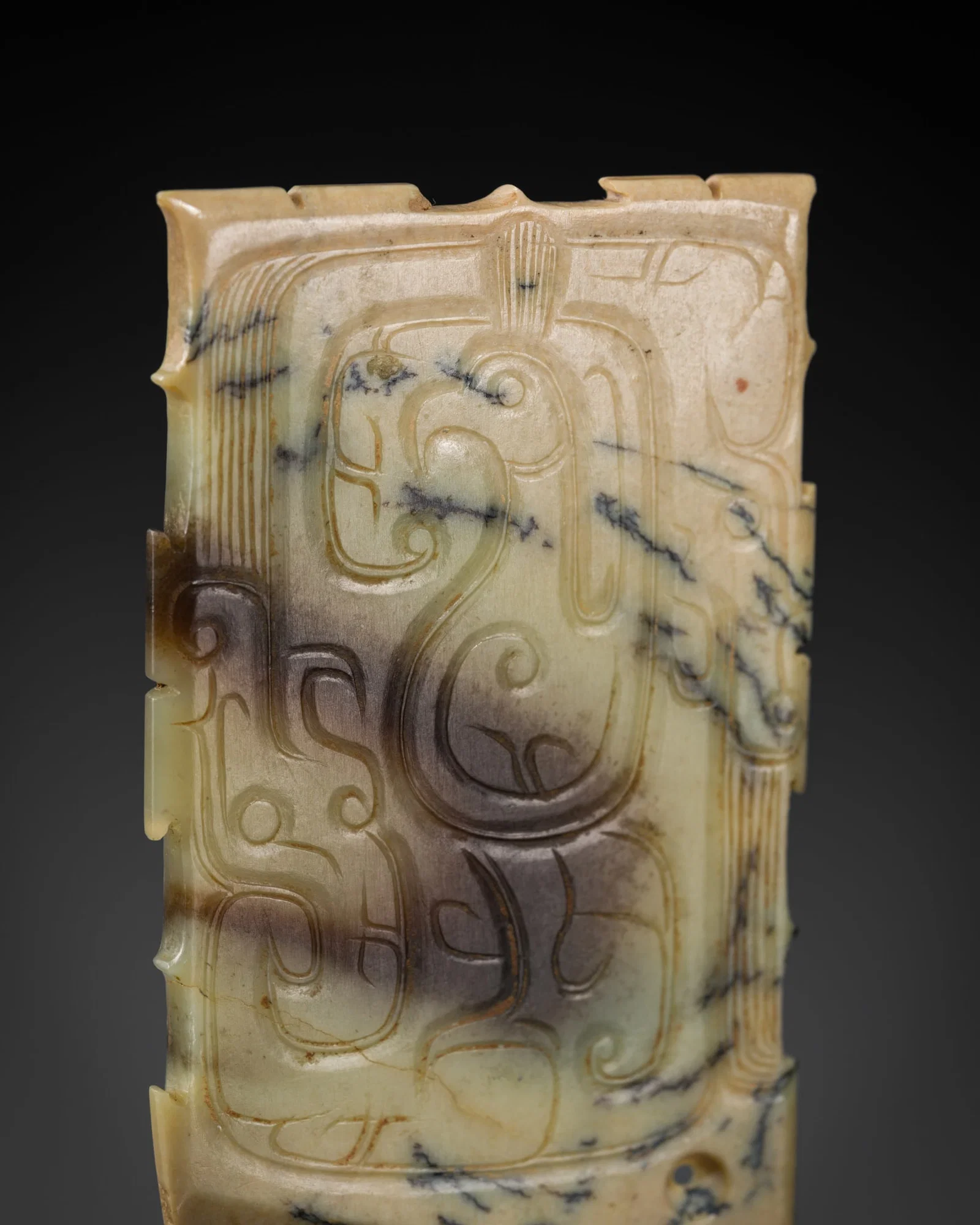 A PALE GREEN AND BROWN JADE 'PHOENIX AND DRAGONS' AXE-SHAPED PENDANT, WESTERN ZHOU DYNASTY