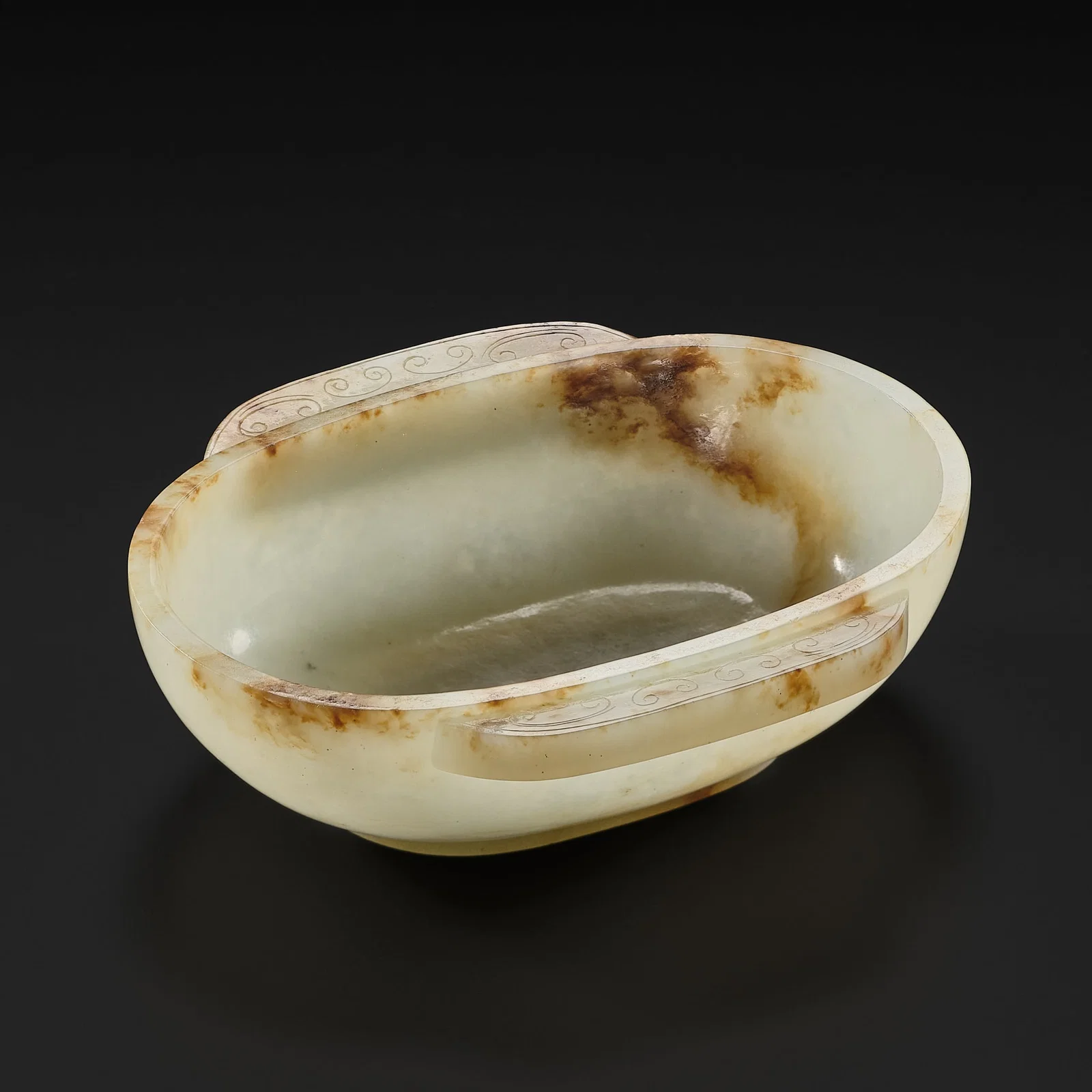 A PALE GREEN AND RUSSET JADE EAR CUP, HAN DYNASTY
