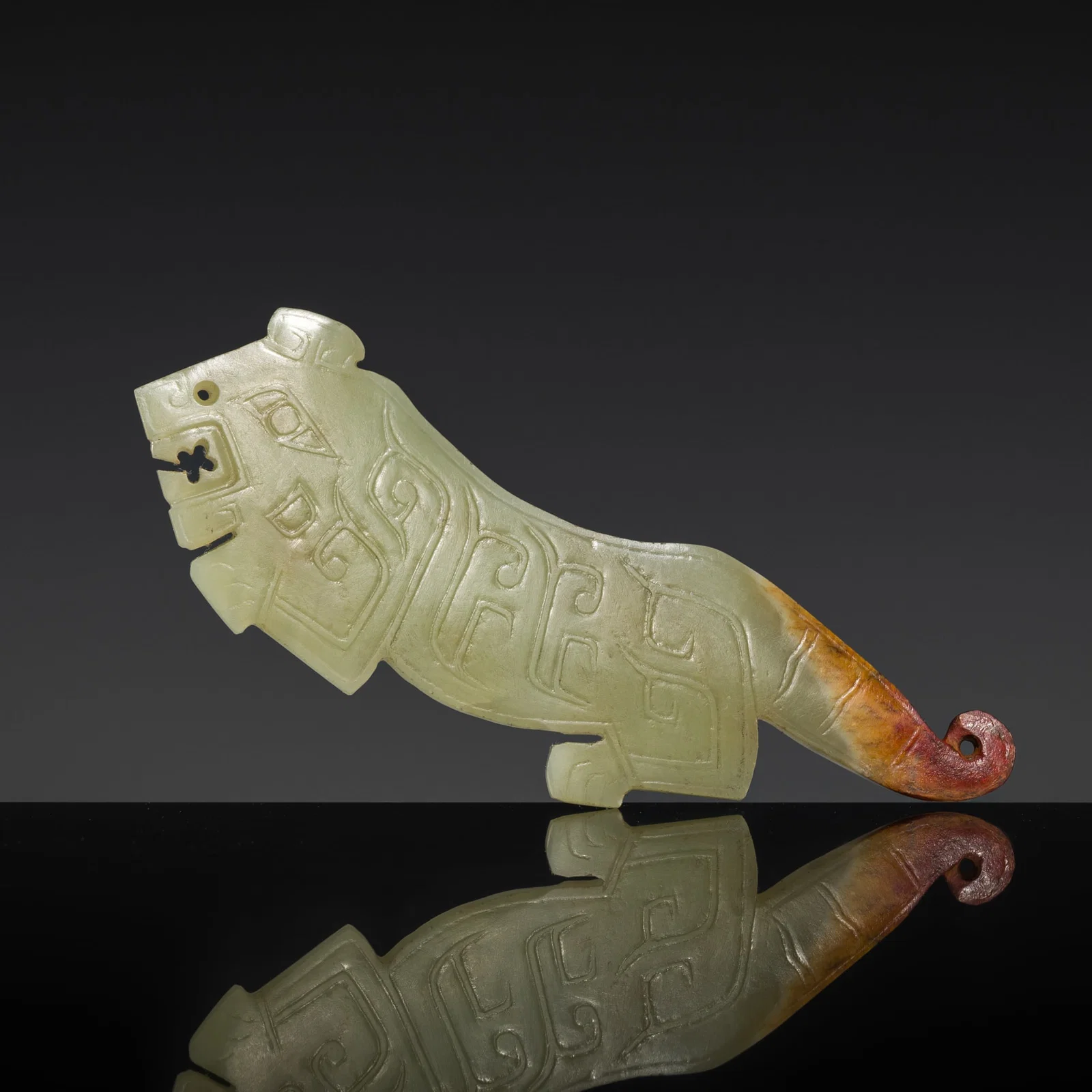 A PALE GREEN AND RUSSET JADE 'TIGER' PENDANT, WESTERN ZHOU DYNASTY