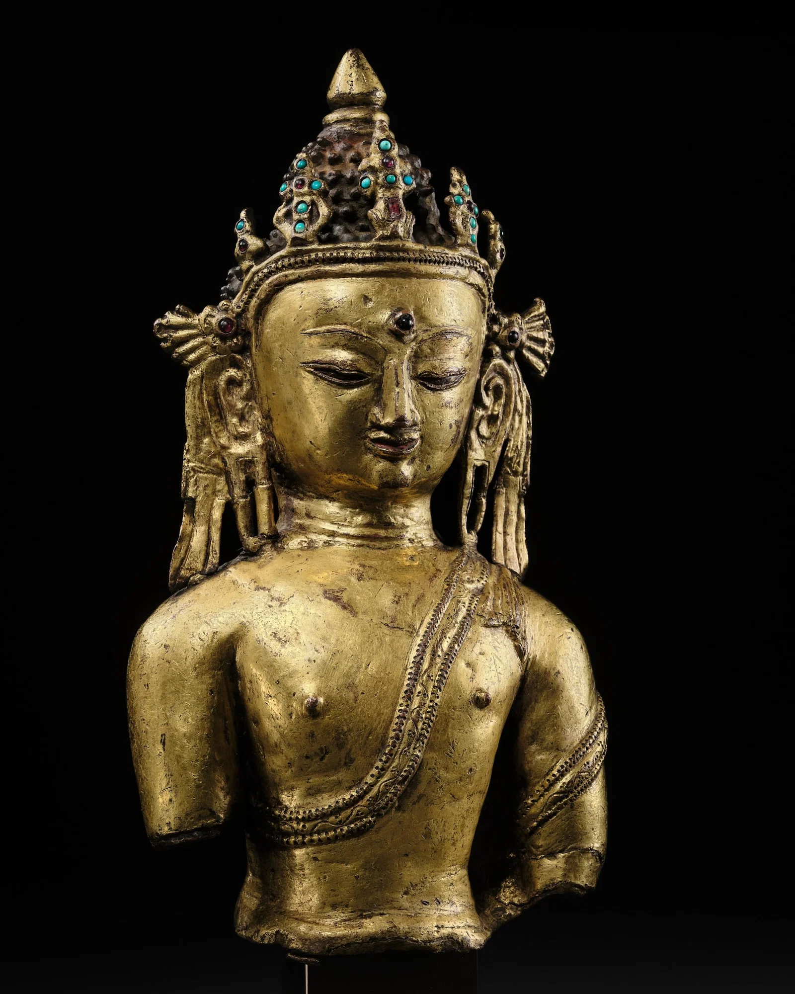 A RARE GILT-BRONZE BUST OF BUDDHA SHAKYAMUNI, EARLY MALLA PERIOD, NEPAL, 14TH-15TH CENTURY