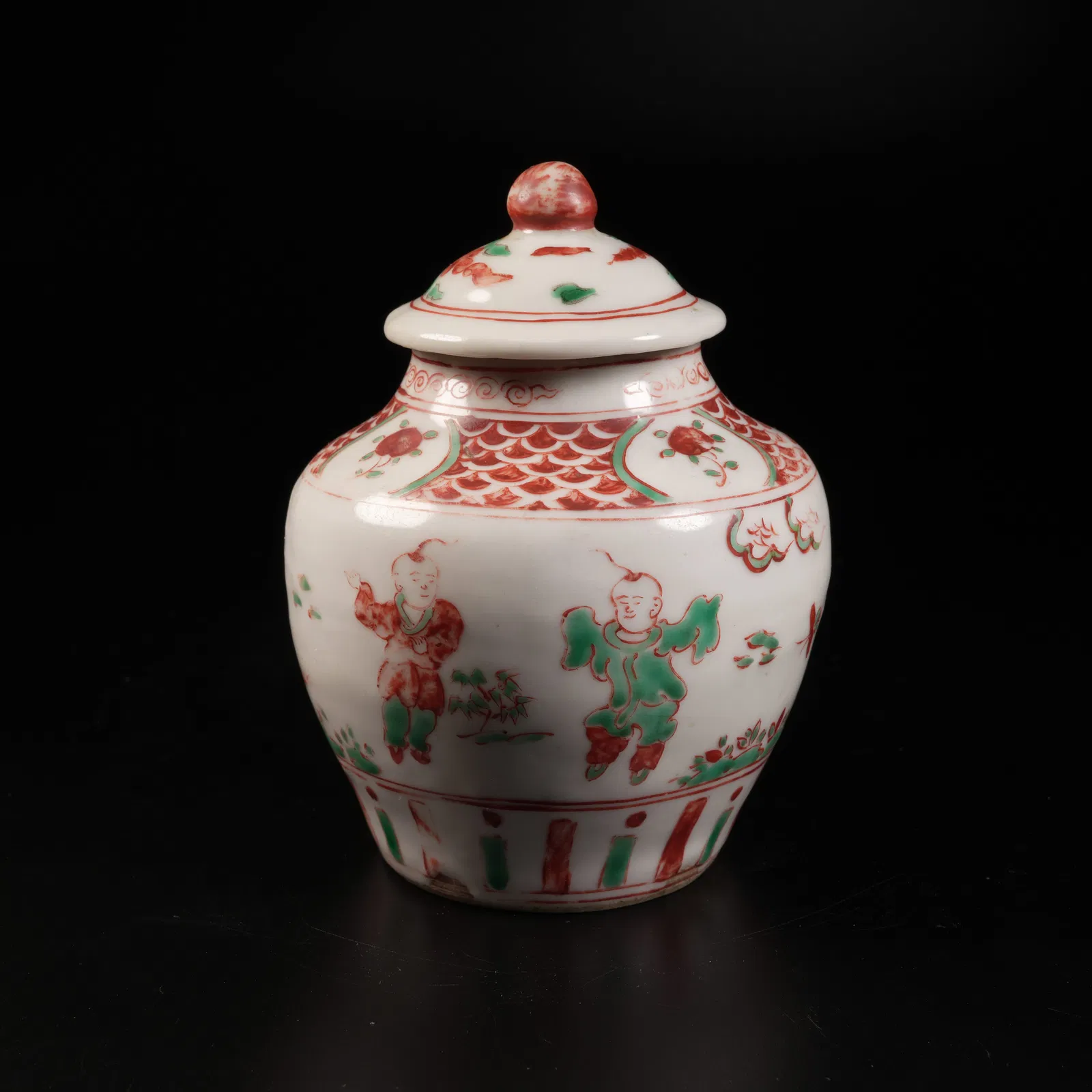 A RED-AND-GREEN ENAMELED COVERED JAR WITH CHILDREN-AT-PLAY MOTIF