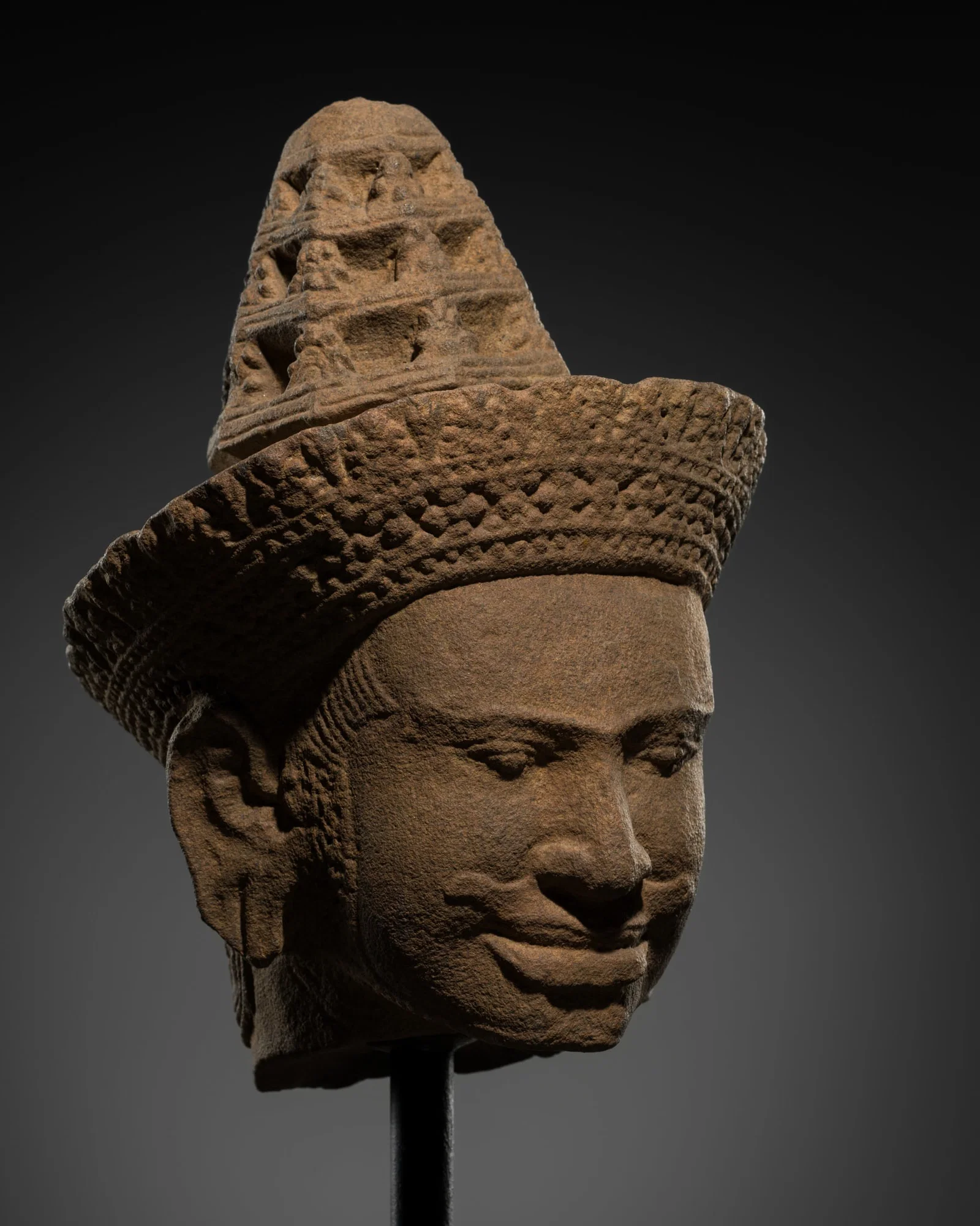 A SANDSTONE HEAD OF A MALE DEITY WITH MOUNT MERU CHIGNON, KHMER, PRE RUP STYLE, 10TH CENTURY