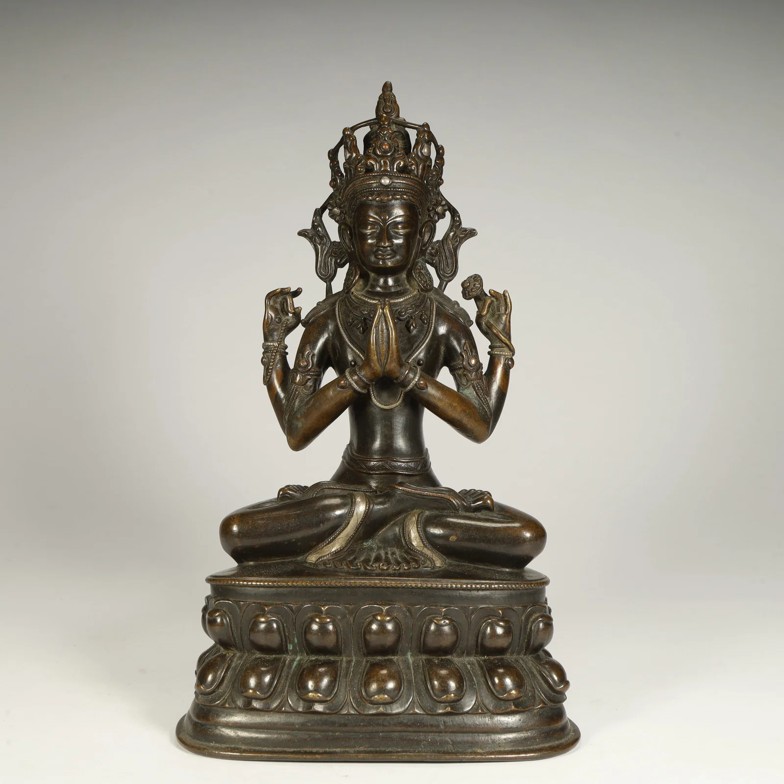 A seated statue of Guanyin with four arms in the bronze dynasty