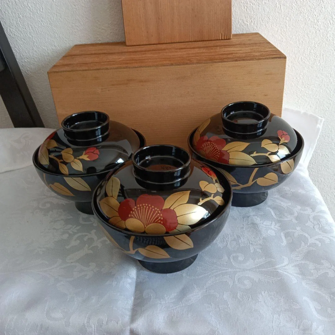 A set of three lacquer bowls with lids. Decorated with floral patterns and embellished with gold