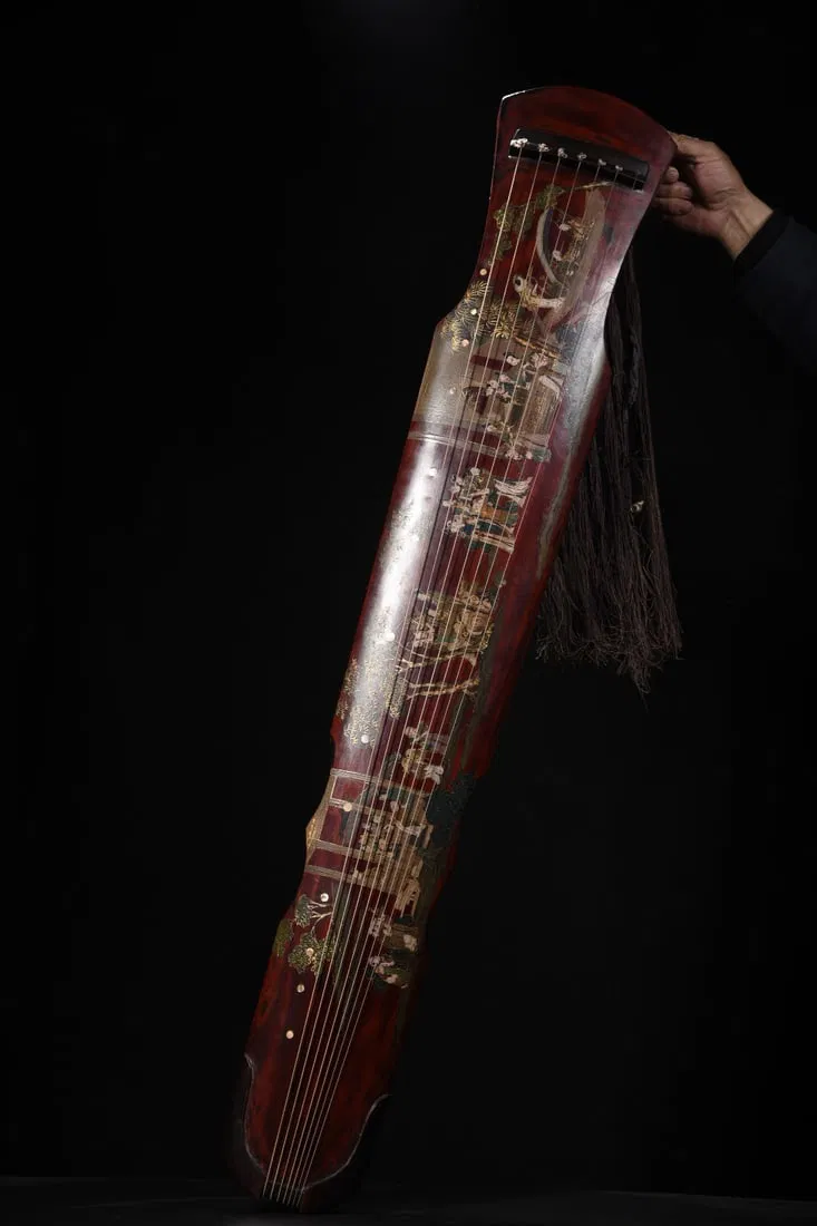 A seven-stringed guqin with a wooden body, lacquered and decorated with a gold-painted design of one
