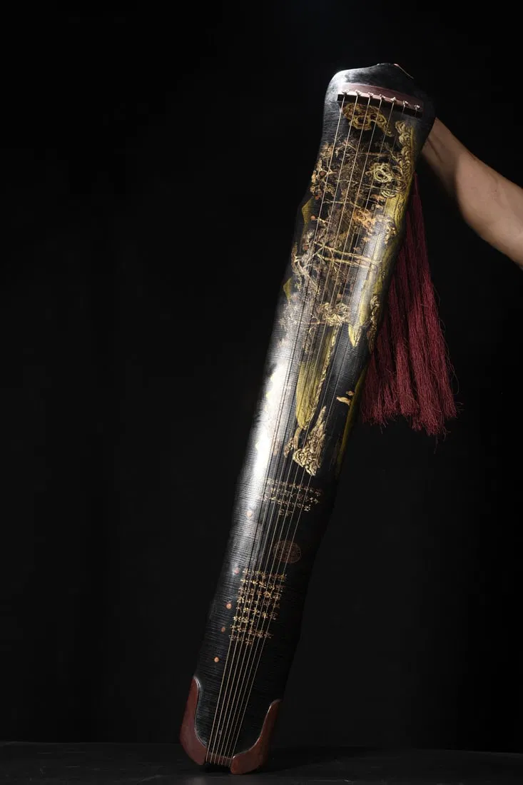 A seven-stringed guqin with a wooden body, lacquered and decorated with gold-painted layered peaks.