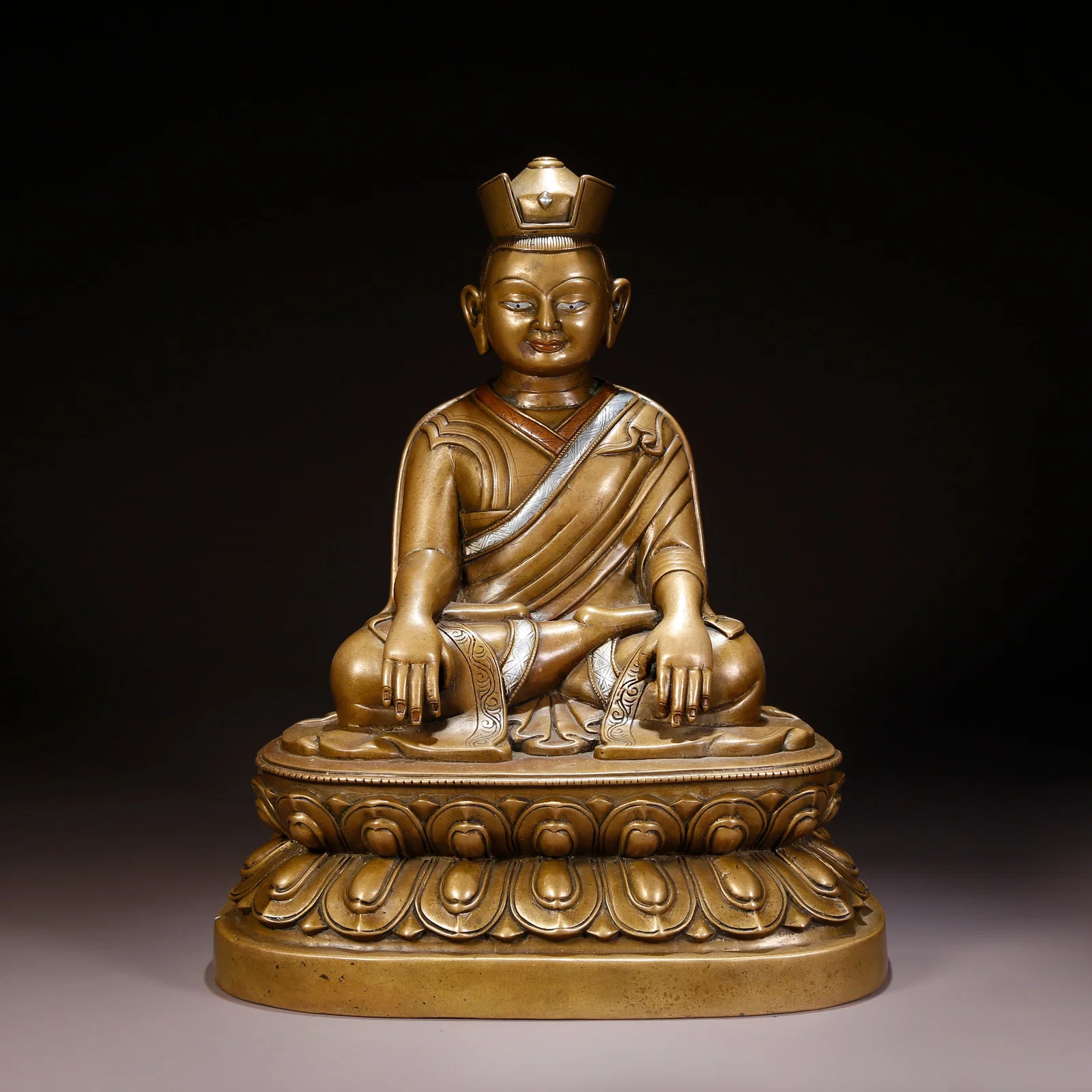 A SILVER- AND RED-COPPER INLAID LAMA FIGURE