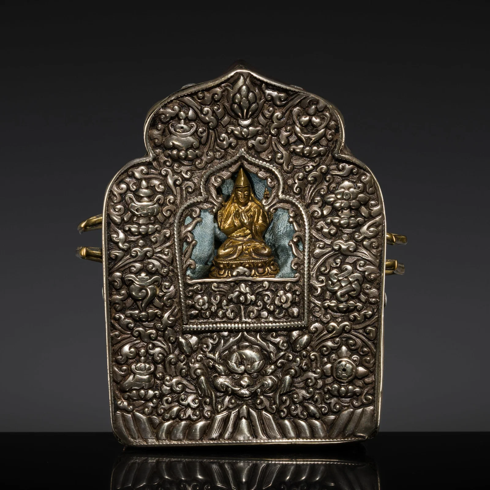 A SILVER REPOUSSÉ PORTABLE AMULET BOX, GAU, CONTAINING A SMALL GILT COPPER ALLOY FIGURE OF