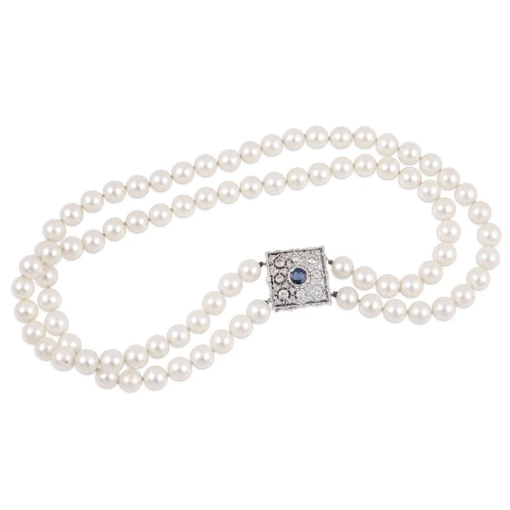 A SINGLE STRAND OF CULTURED PEARLS WITH 18KT GOLD CLASP SET WITH SAPPHIRE AND DIAMONDS, BY