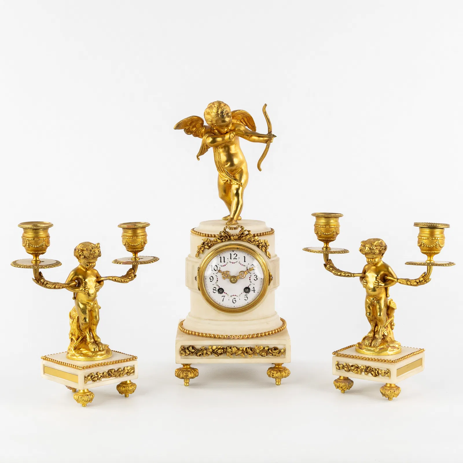 A Three-piece Mantel Garniture, clock and candelabra, gilded bronze and marble, mounted with Cupid