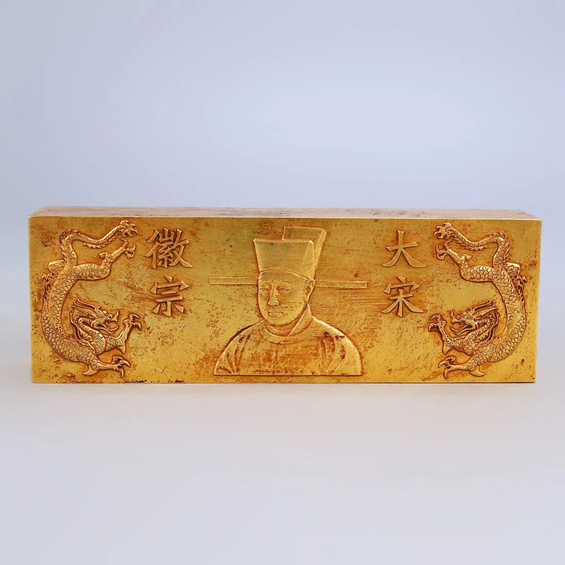 A treasured gilt-copper brick, engraved with relief carvings.