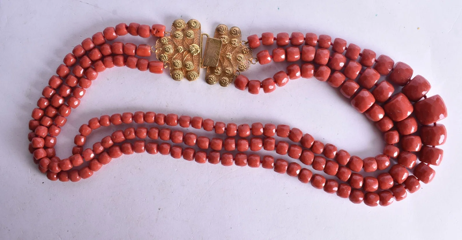 A Triple Strand Coral Bead Necklace with an 18 Carat Gold Clasp. Length 63cm, Largest Bead 23mm