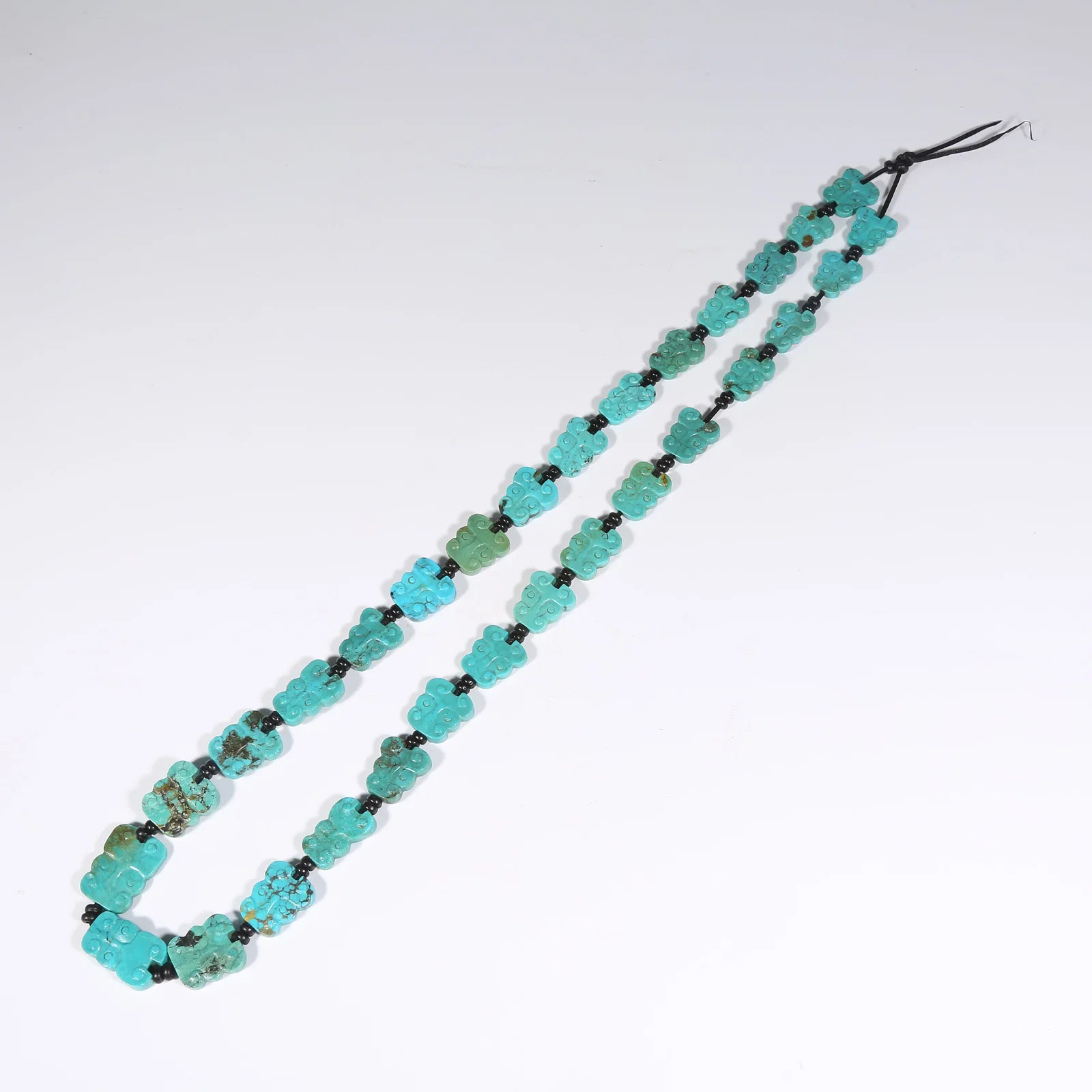 A TURQUOISE PENDANT WITH BEAST FACE MOTIF