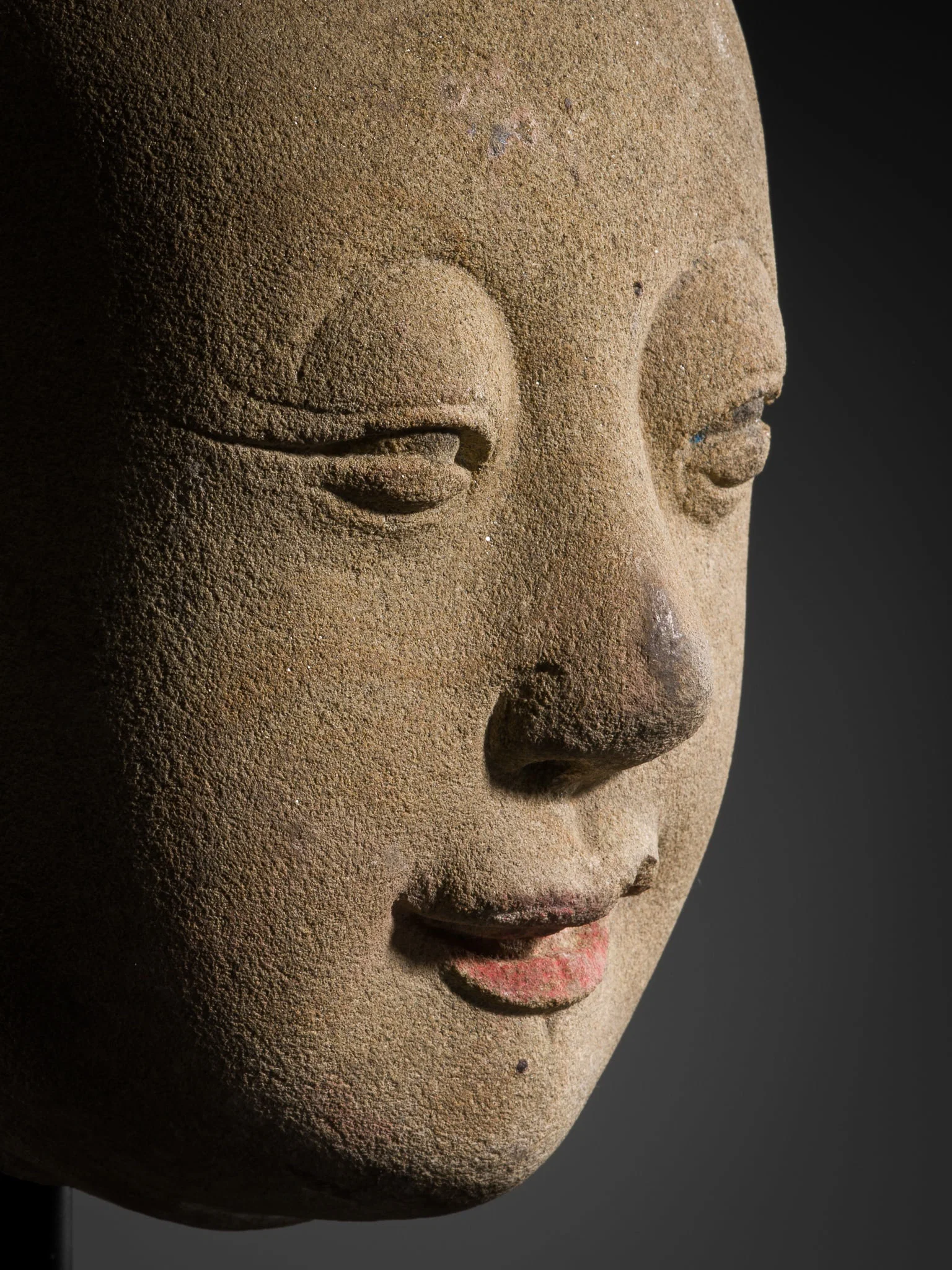AN EXCEPTIONALLY RARE AND EARLY STONE HEAD OF A YOUTHFUL LUOHAN, TANG DYNASTY (618-907)