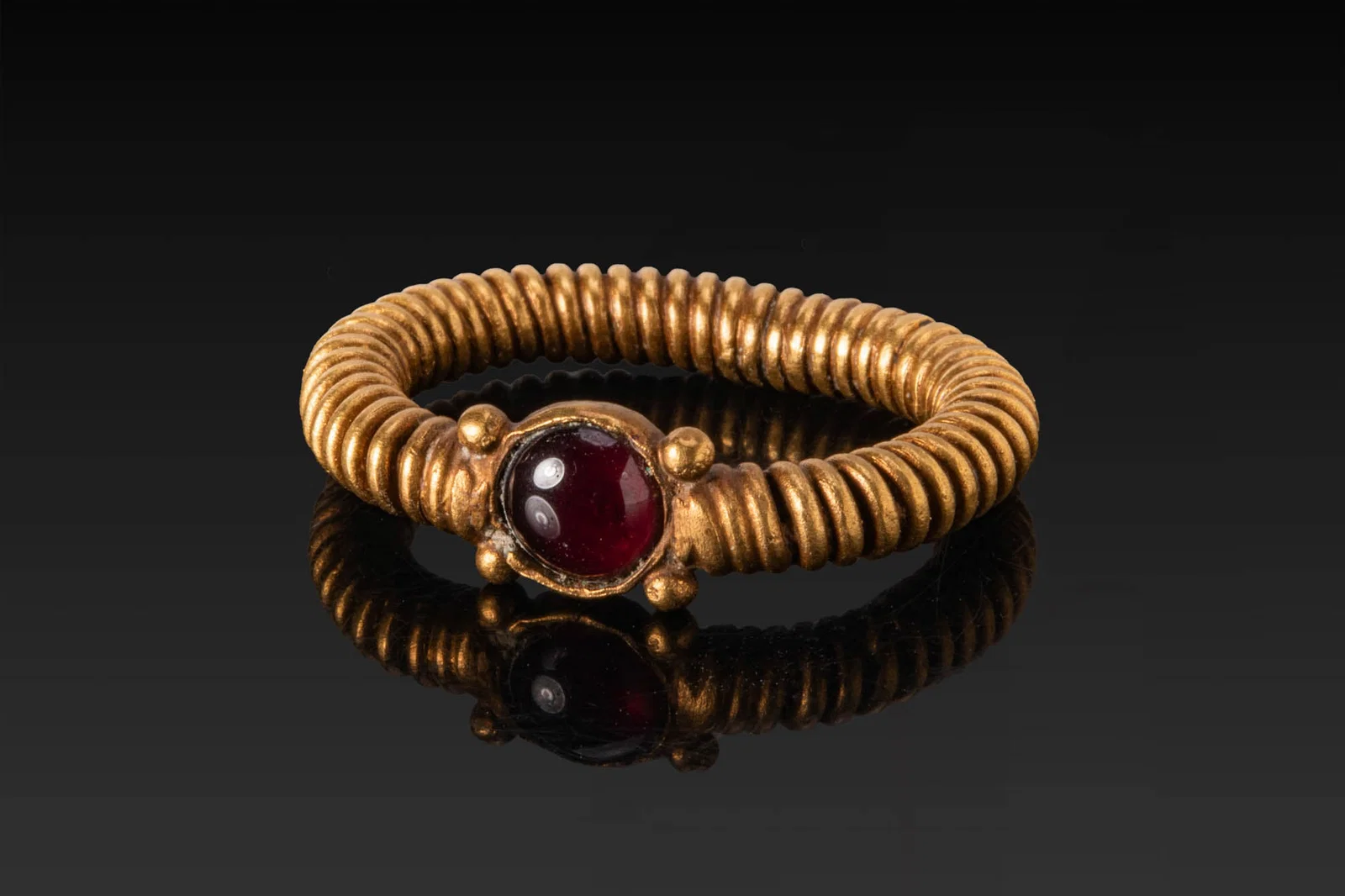 RARE PHOENICIAN HIGH KARAT GOLD COILED RING WITH RED GARNET CABOCHON AND PELLETS